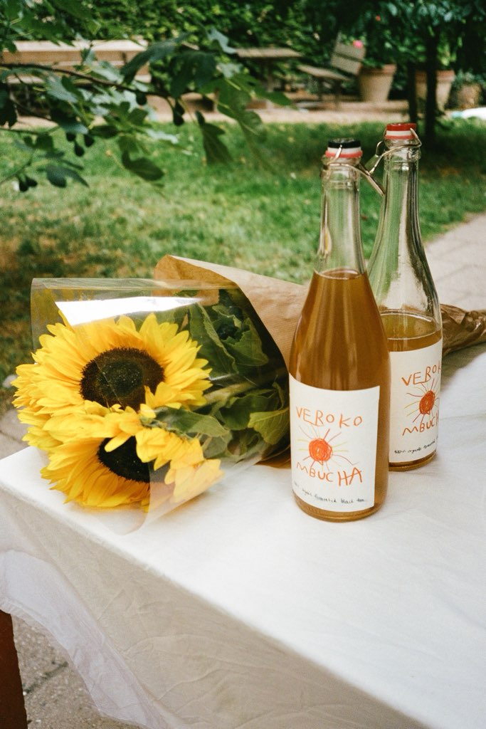 Two bottles of Verokombucha next to a bouquet of sunflowers.